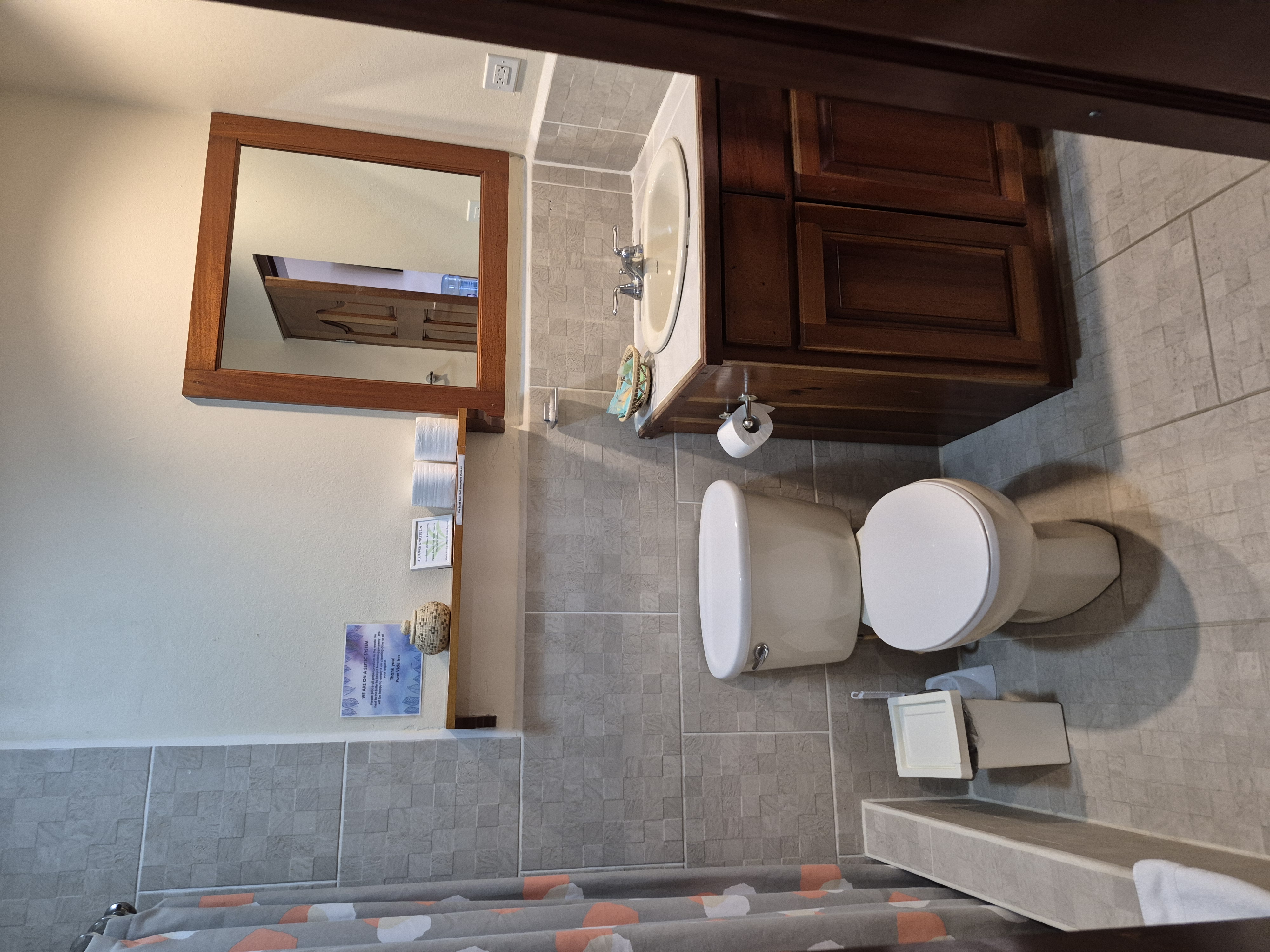 Small bathroom with a toilet, sink with wooden cabinet, and tiled walls.
