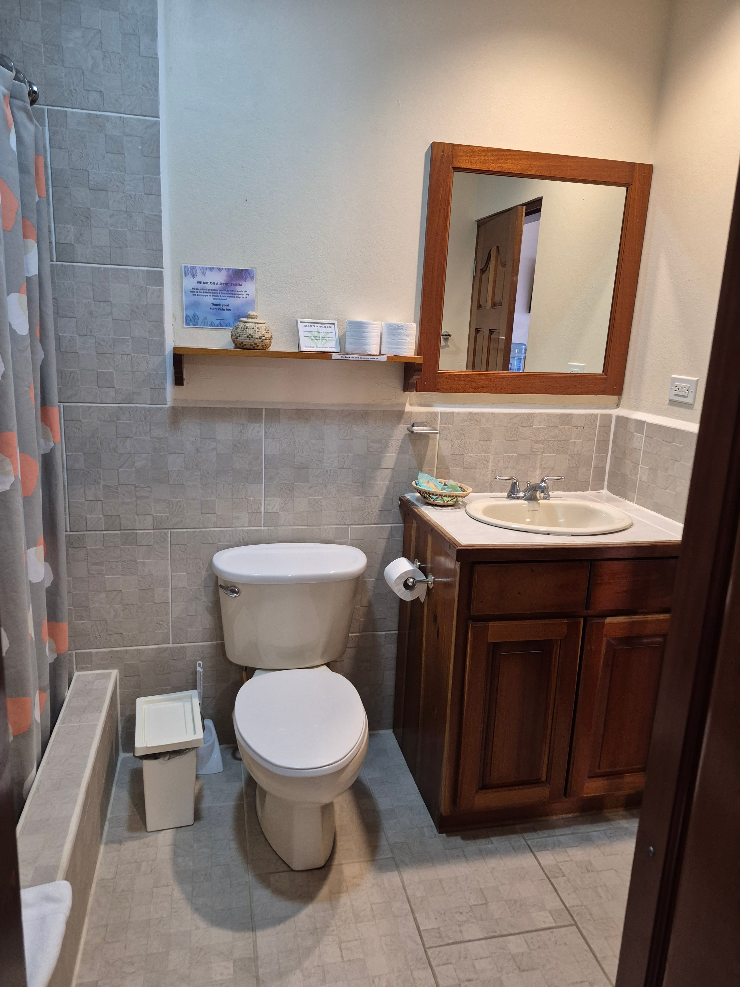 Small bathroom with a toilet, sink with wooden cabinet, and tiled walls.