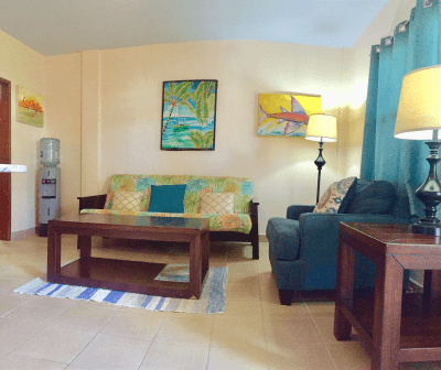 Well lit room with blue curtans, seating area with coffee table, and two side tables with lamps