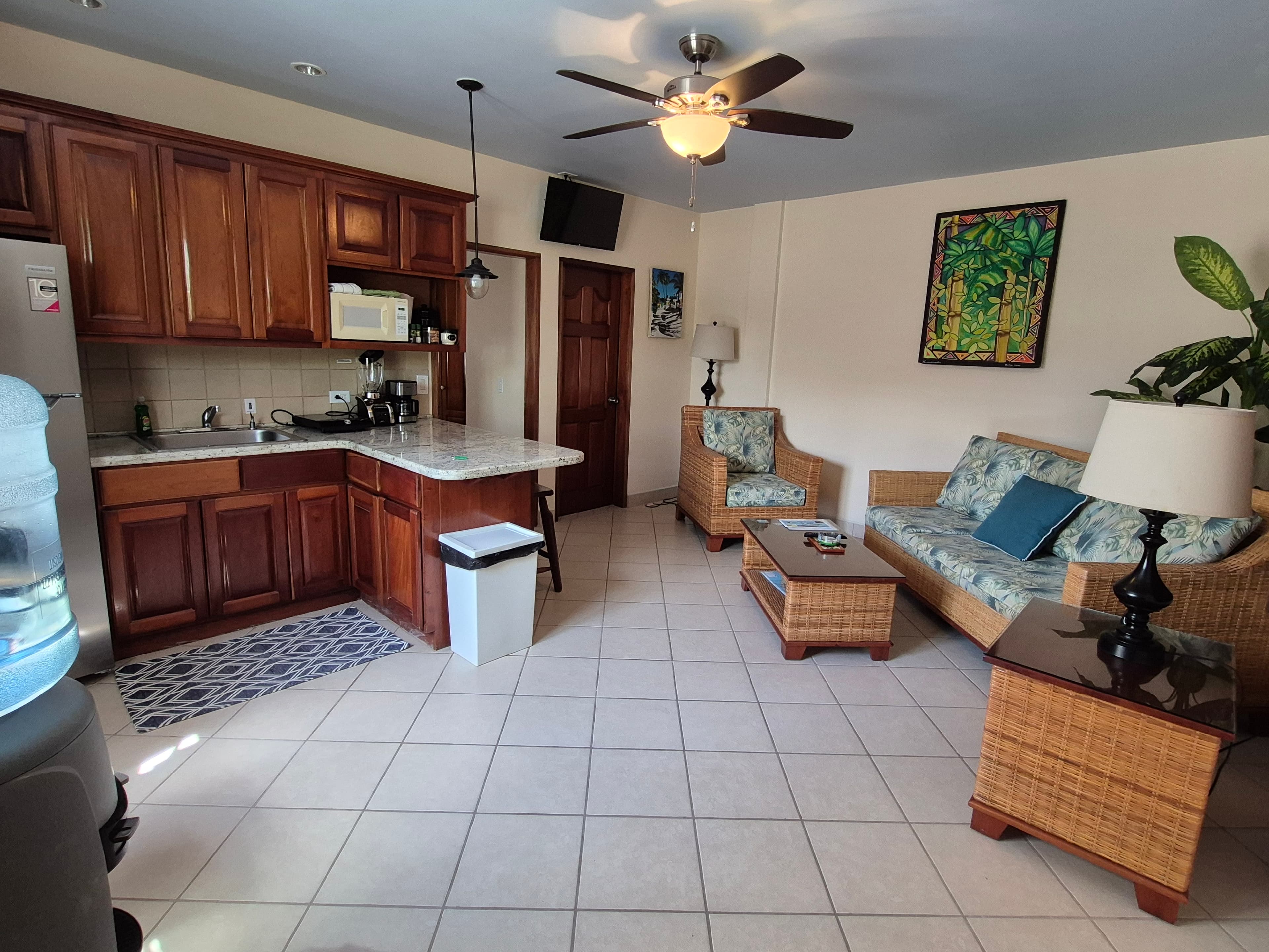 Living area with seating and coffee table that opens to a full kitchen.