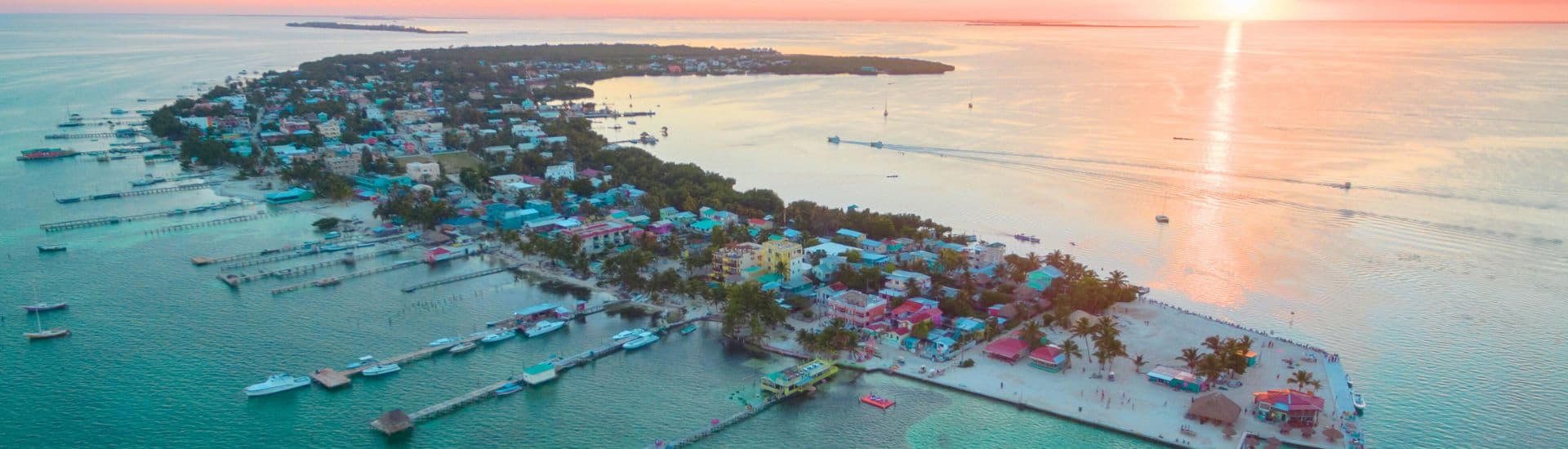 Aerial view of a colorful island with beaches and boats at sunset.